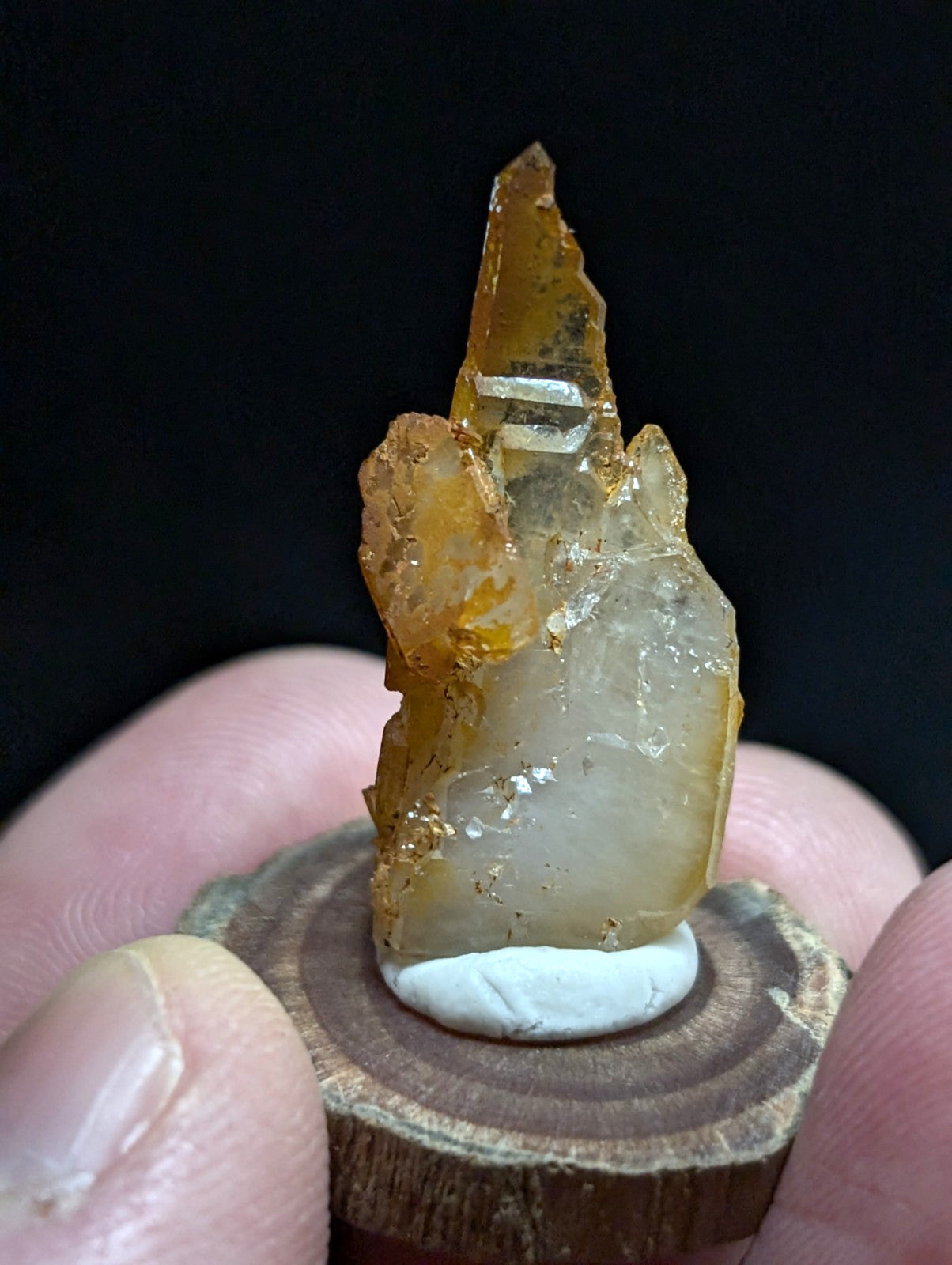 A translucent amber-colored mineral crystal with a pointed, jagged top and layered internal structure.