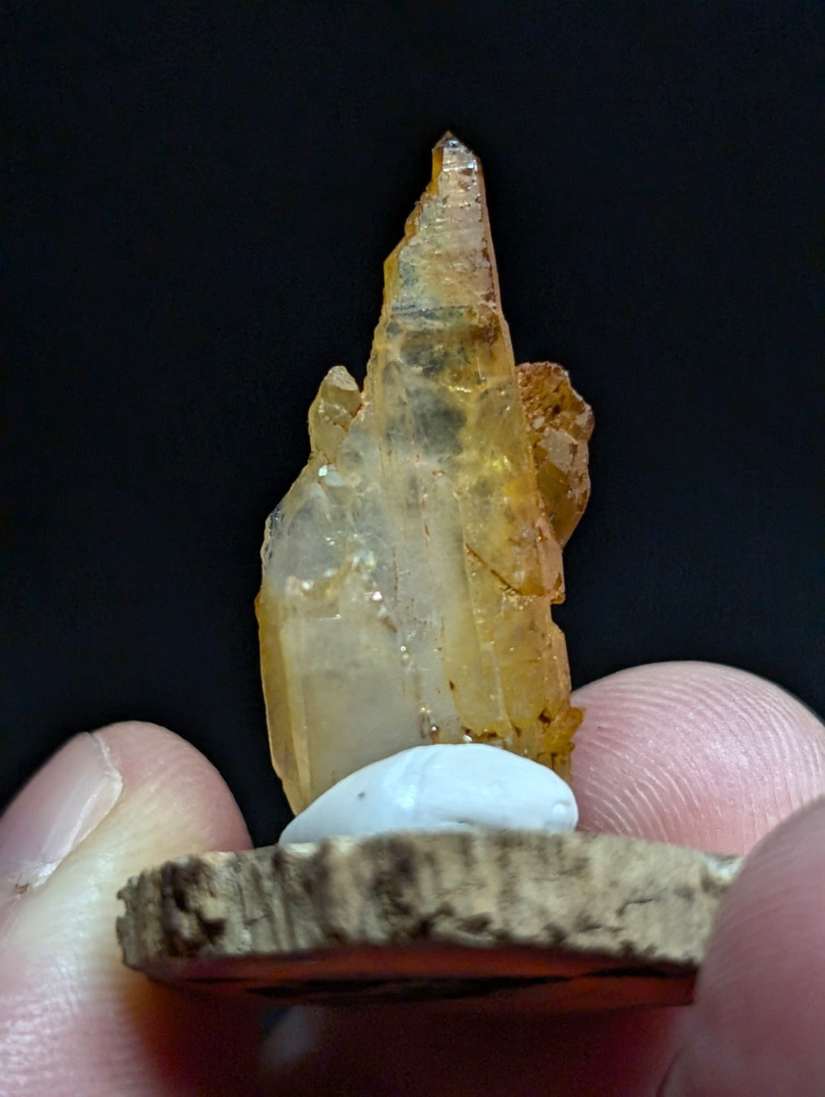 A translucent yellow-orange crystal with a pointed, jagged tip and natural mineral inclusions.
