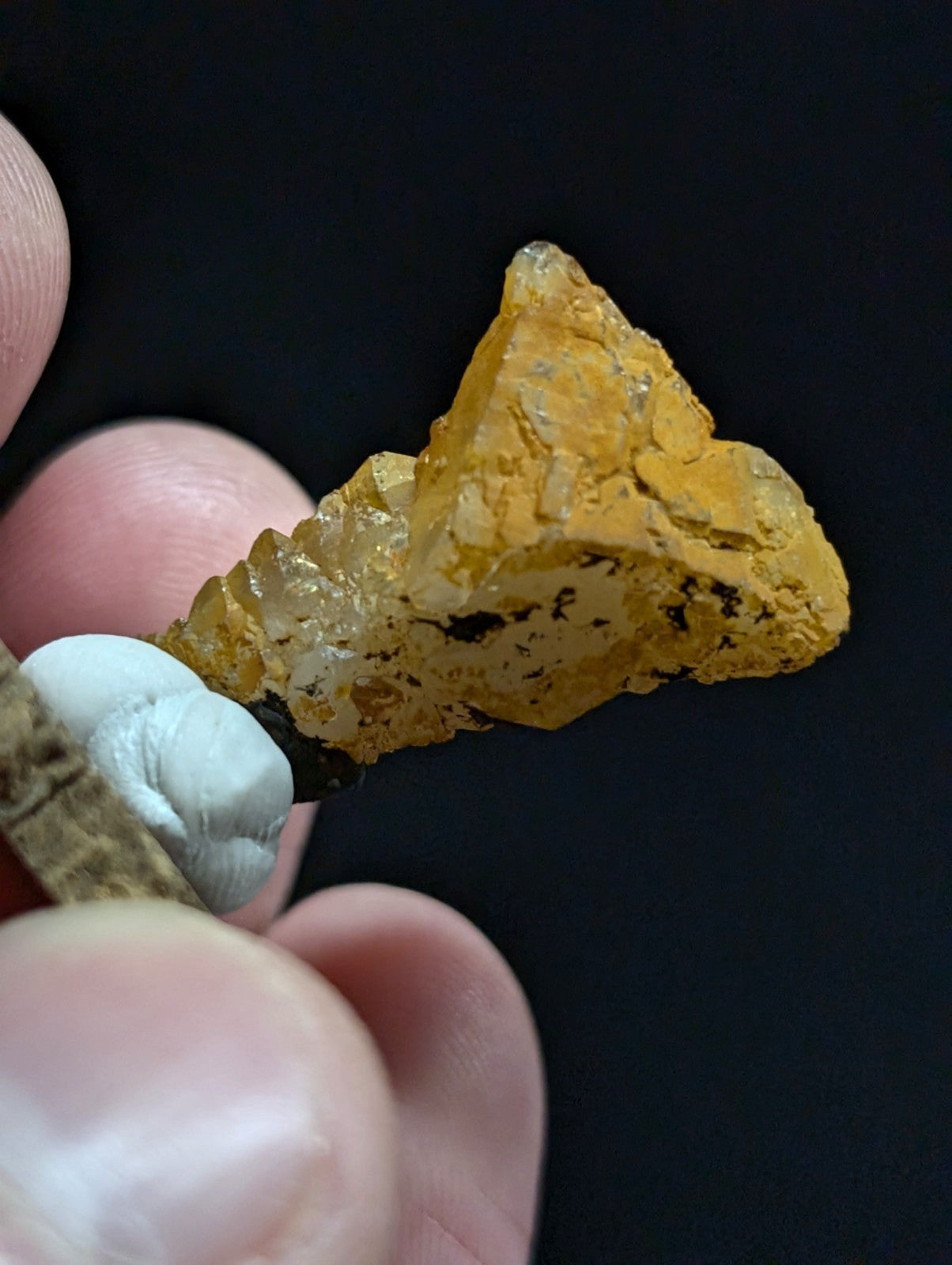 A translucent golden-yellow crystal with a rough, jagged surface and embedded dark inclusions.