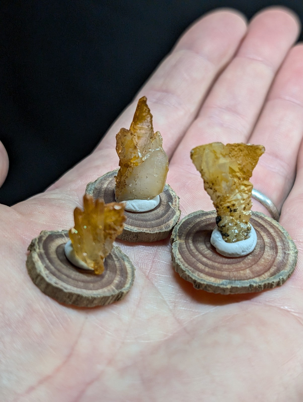 Three amber-colored, crystalline flame-shaped ornaments mounted on circular wooden slices.