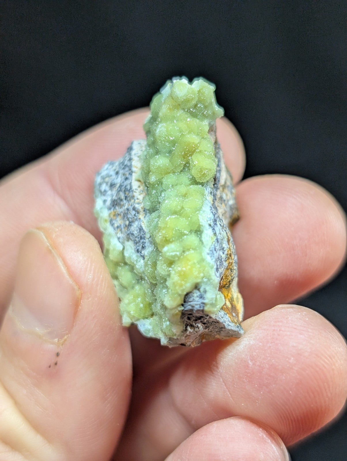 A vibrant green, crystalline mineral specimen with a textured surface and earthy matrix.