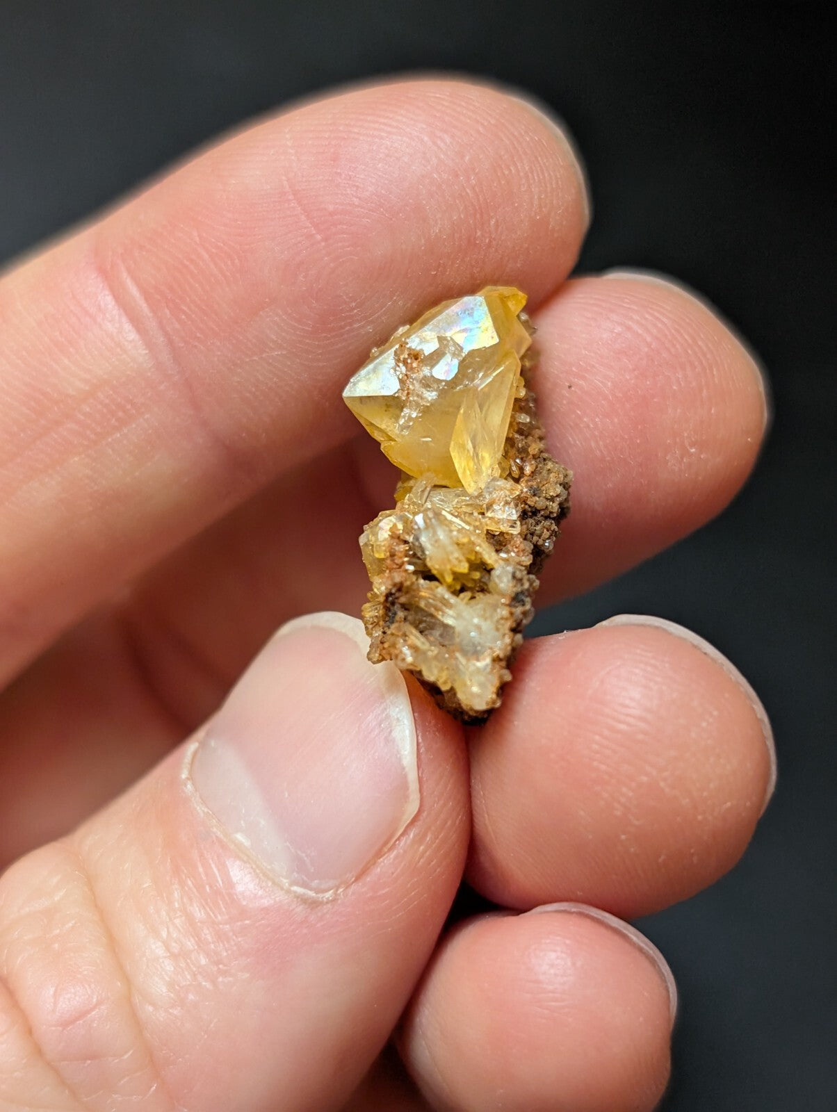 A translucent golden-yellow crystal cluster with a faceted, gem-like top and earthy brown matrix base.