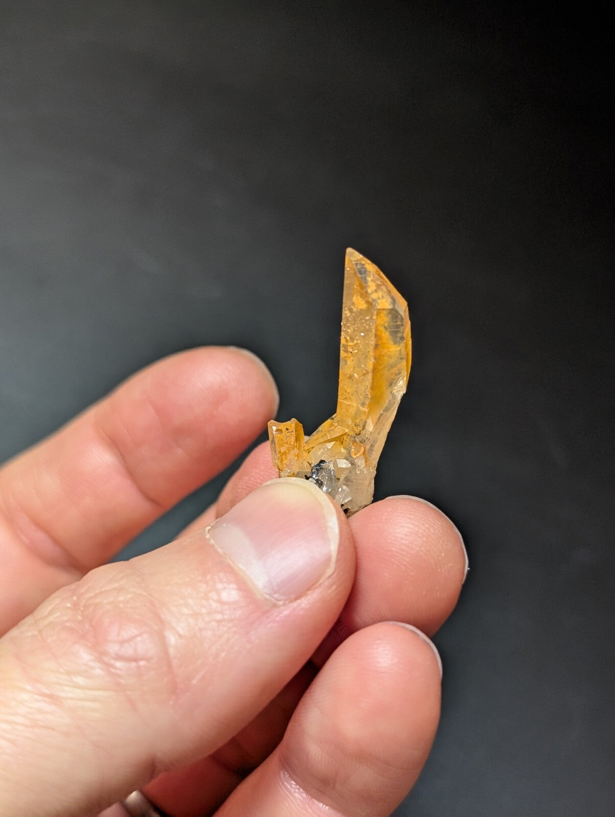 A translucent amber-colored crystal with a pointed, faceted tip and visible internal inclusions.