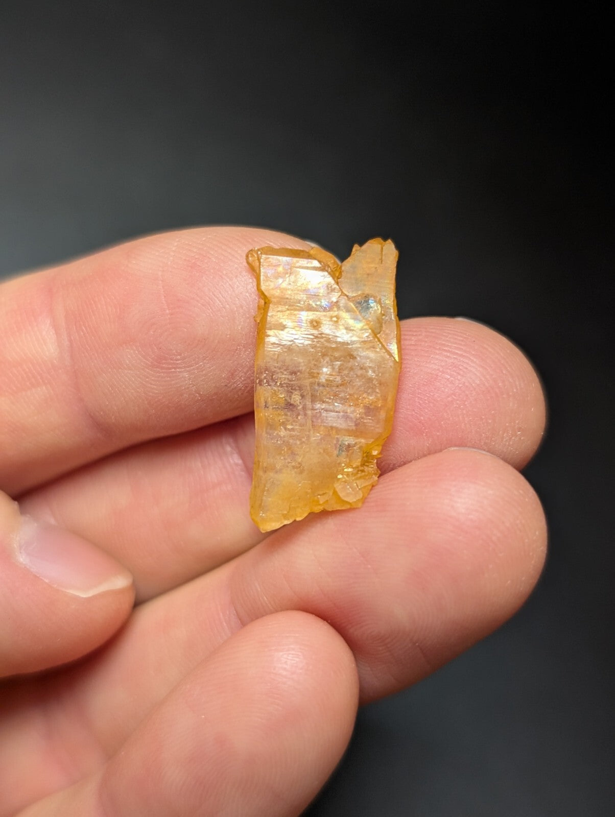 A translucent amber-colored crystal fragment with visible internal striations and a slightly jagged, natural edge.