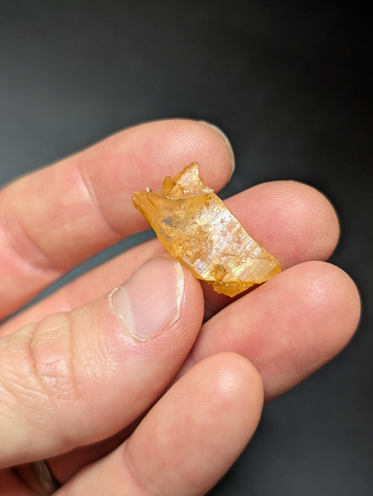 A translucent amber-colored glass shard with a rough, jagged edge and subtle internal reflections.