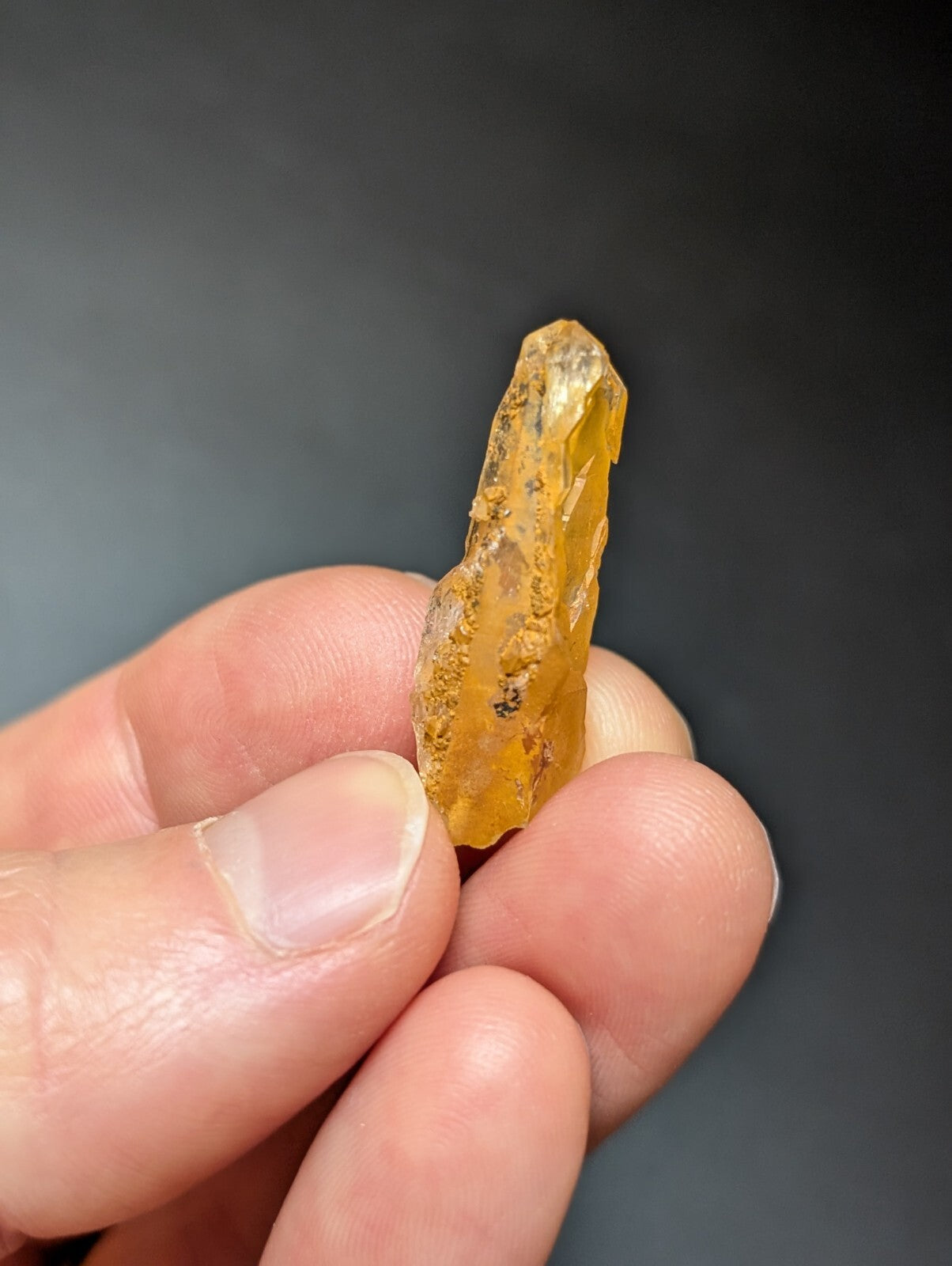 A translucent amber-colored crystal with a rough, jagged surface and natural inclusions.