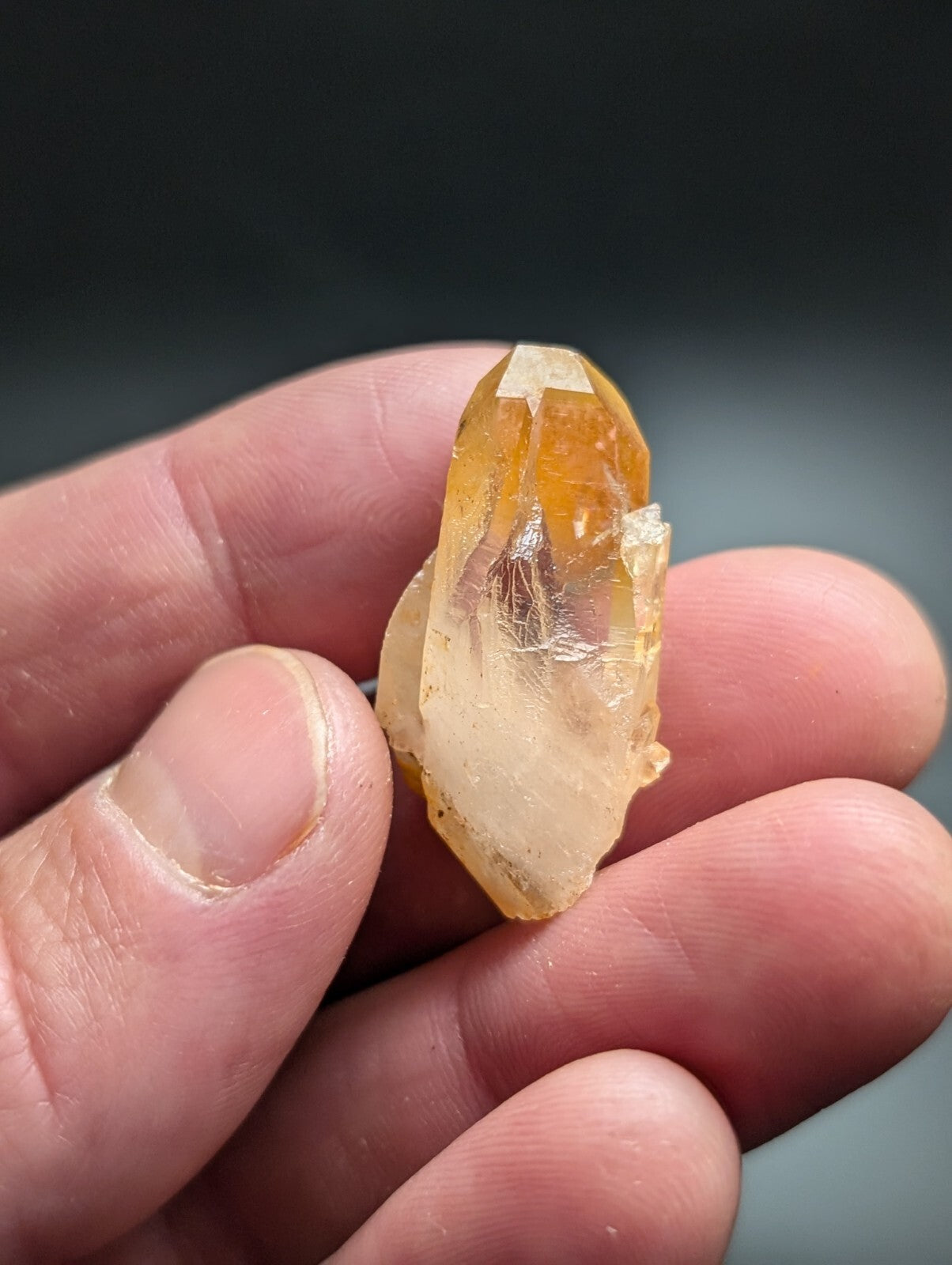 A translucent golden-yellow crystal with a pointed, faceted top and rougher base.