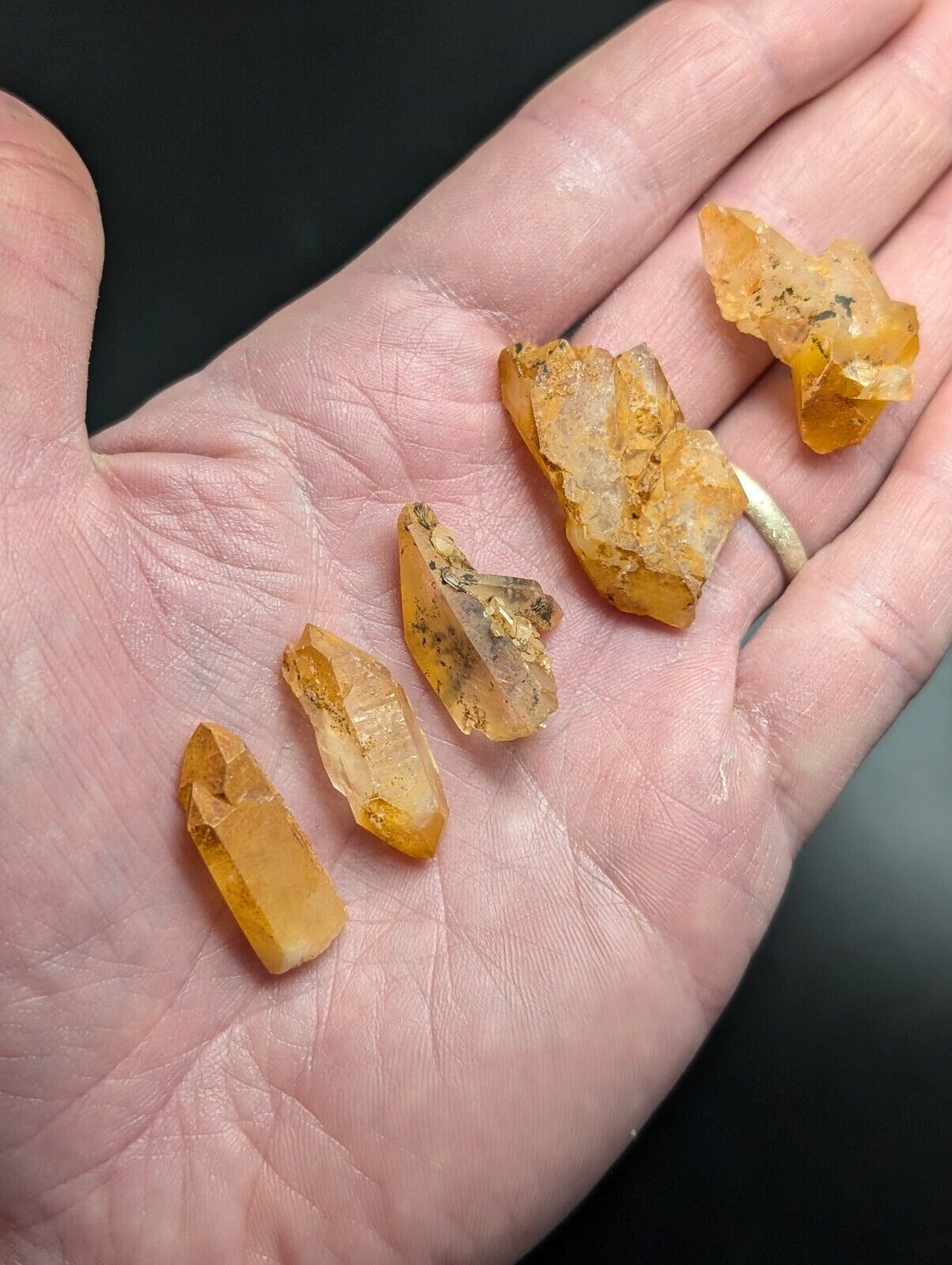 Hand holding orange quartz crystals.