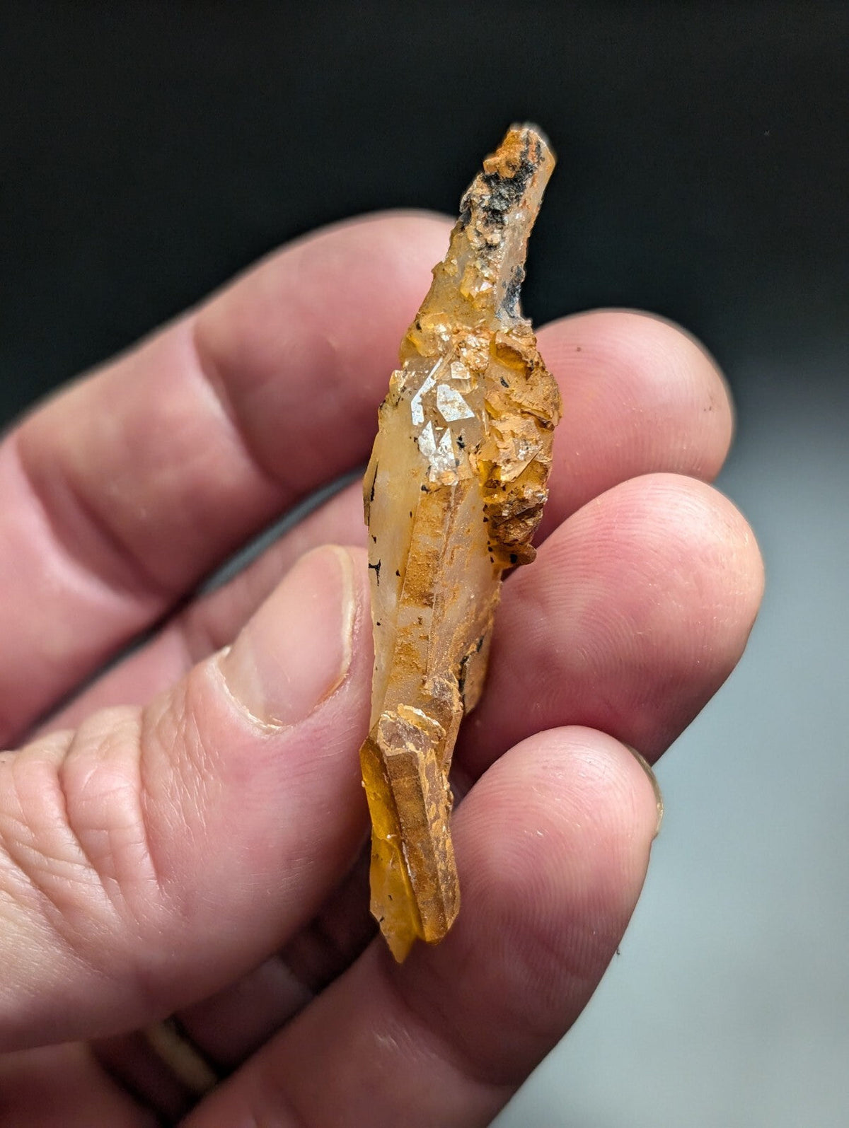 A translucent amber-colored crystal with a rough, earthy exterior and sharp, faceted edges.