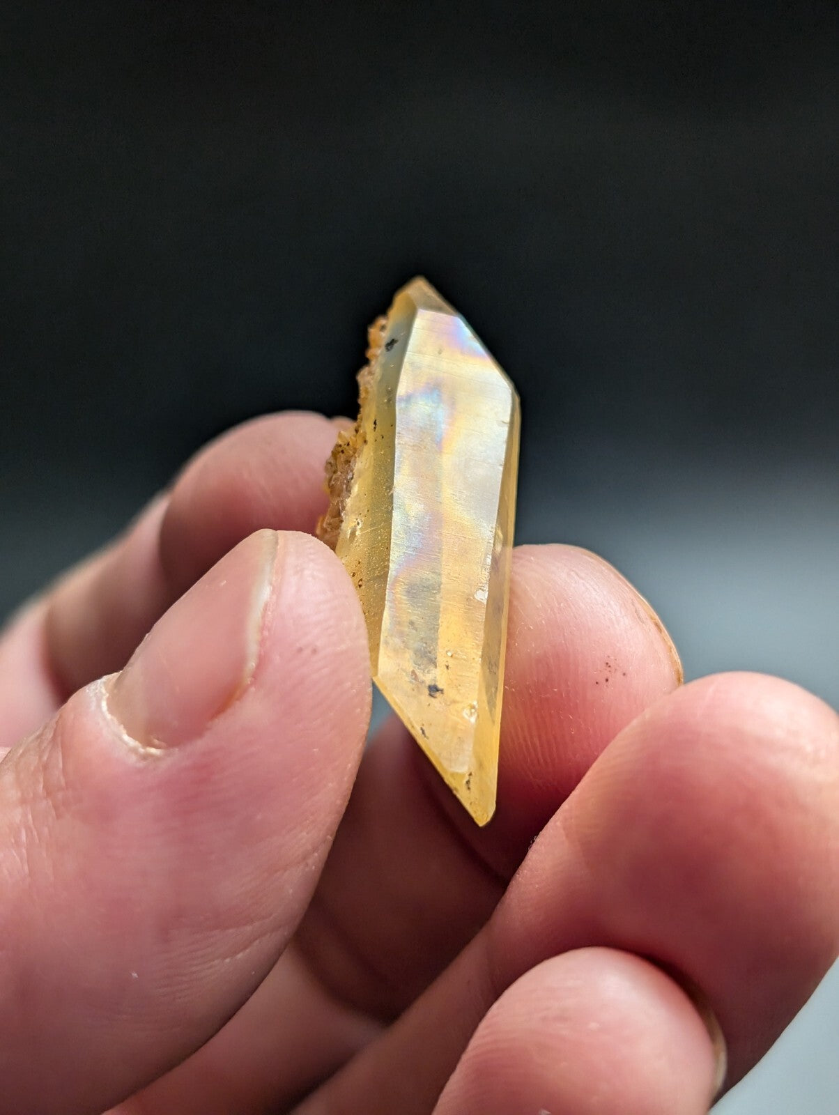 A translucent yellow opal crystal with a faceted, pointed shape and subtle iridescent flashes.