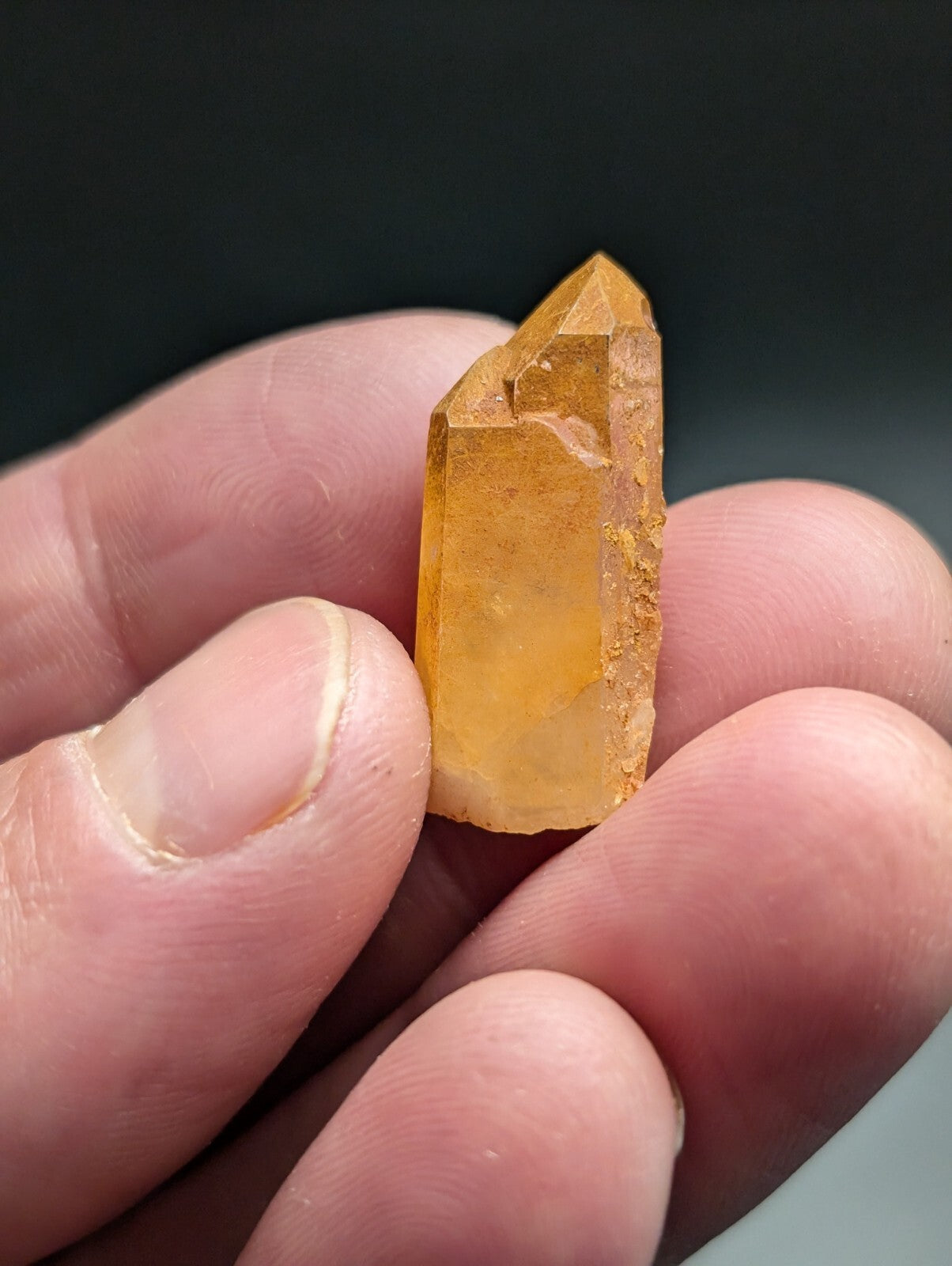 A translucent golden-yellow crystal with a pointed, faceted top and rougher sides.
