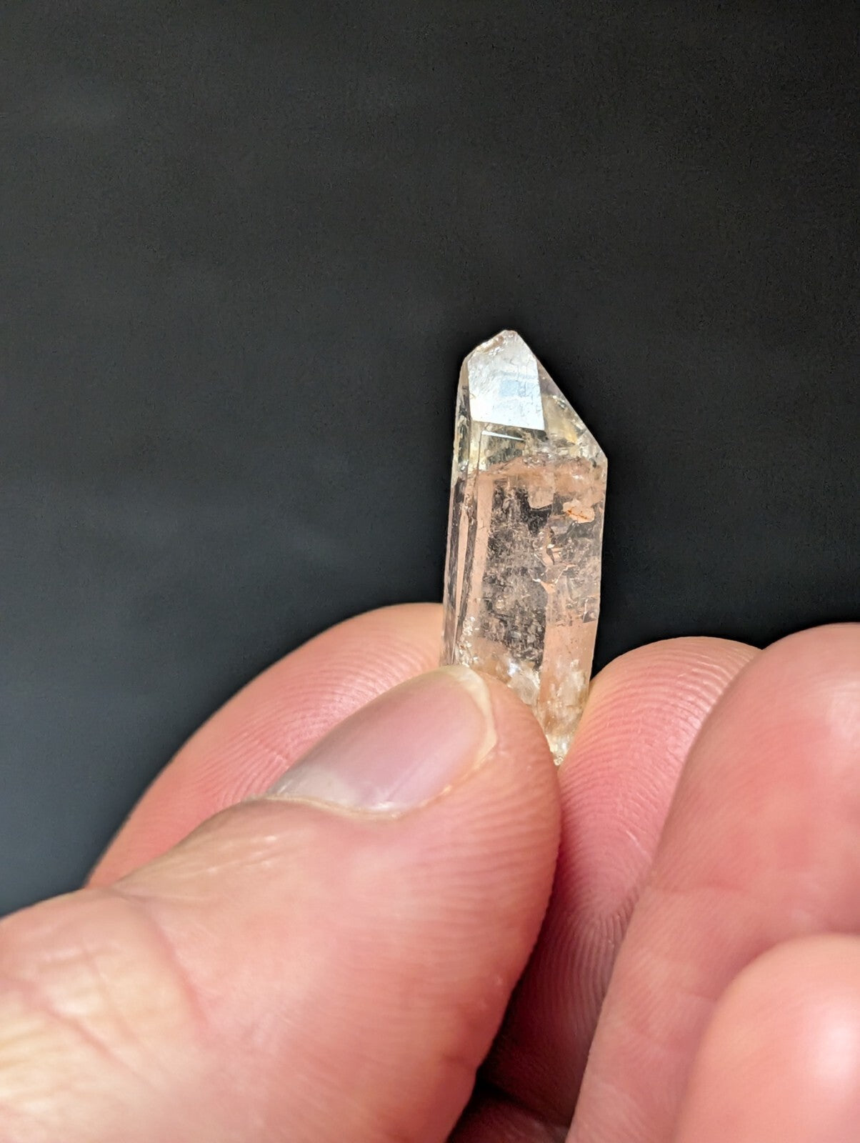 A translucent, clear quartz crystal with a pointed tip and visible internal inclusions.