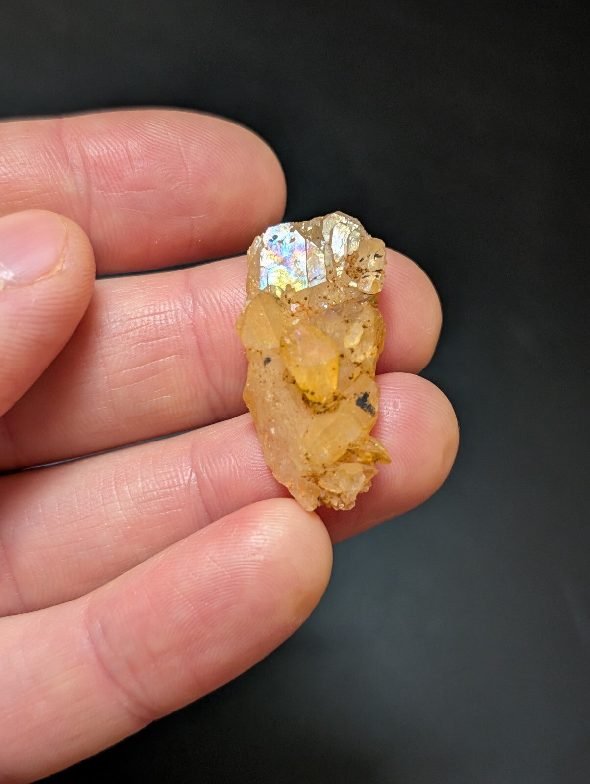 A translucent golden-yellow crystal cluster with a faceted, iridescent top and rougher, earthy base.