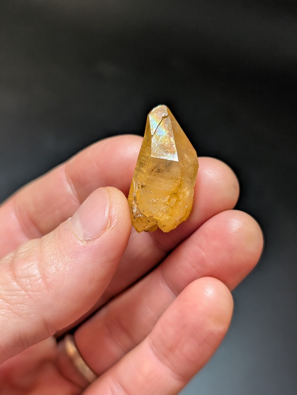 A translucent golden-yellow citrine crystal with a pointed, faceted tip and subtle internal inclusions.