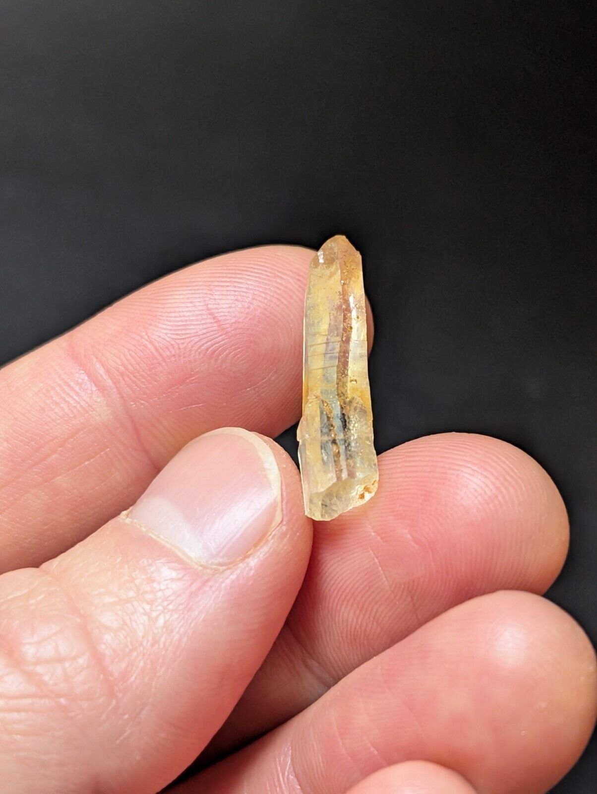 Translucent yellow crystal held in hand.
