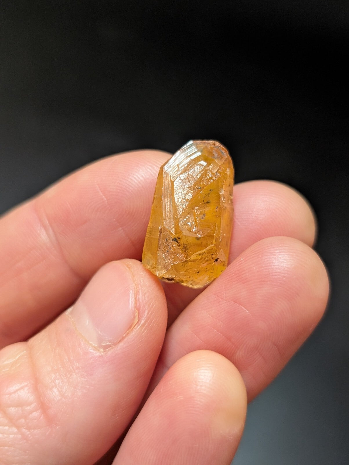 A translucent amber-colored crystal with a faceted, geometric shape and visible internal inclusions.