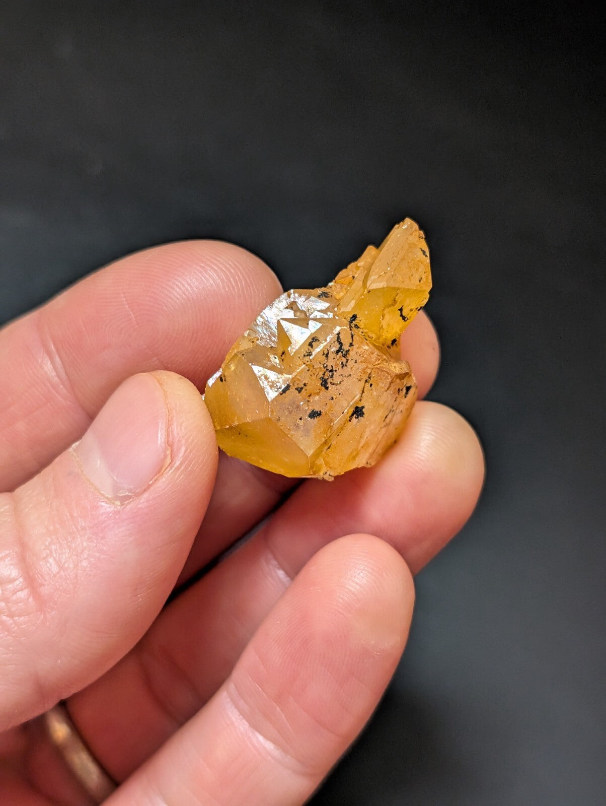A translucent amber-colored crystal with sharp, faceted edges and dark inclusions.