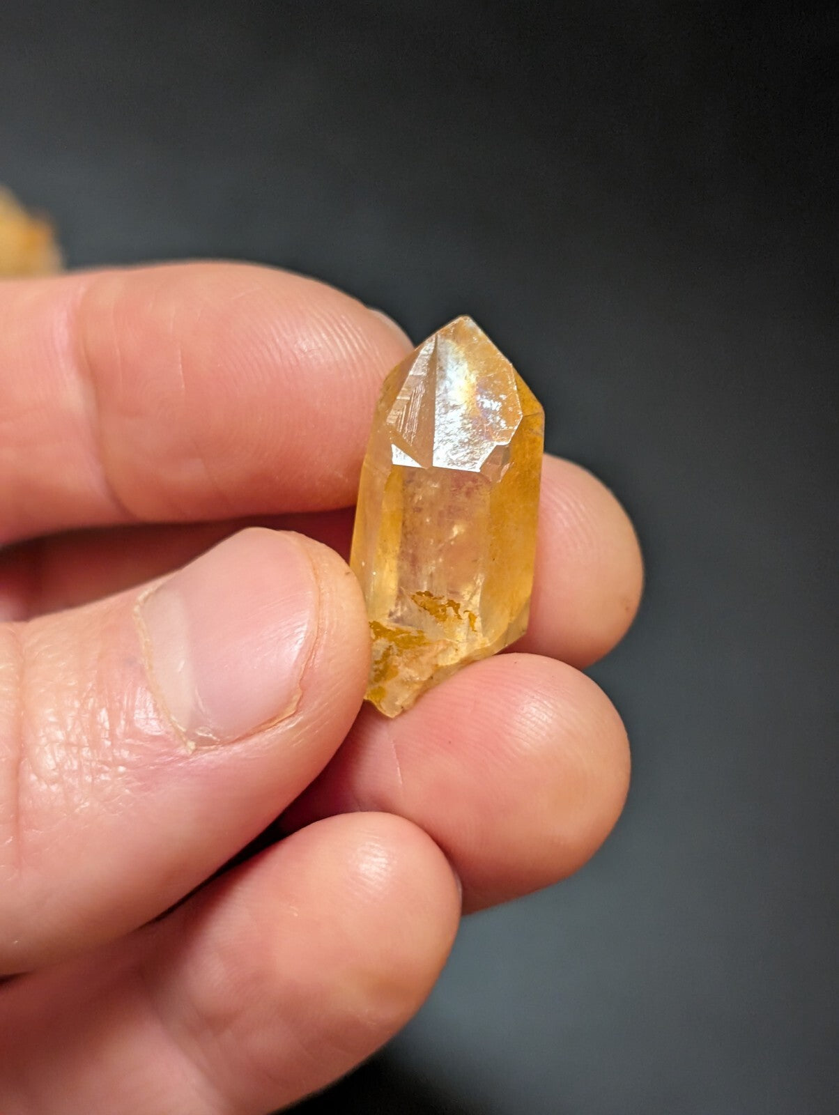 A translucent golden-yellow citrine crystal with a pointed, faceted top and natural inclusions.