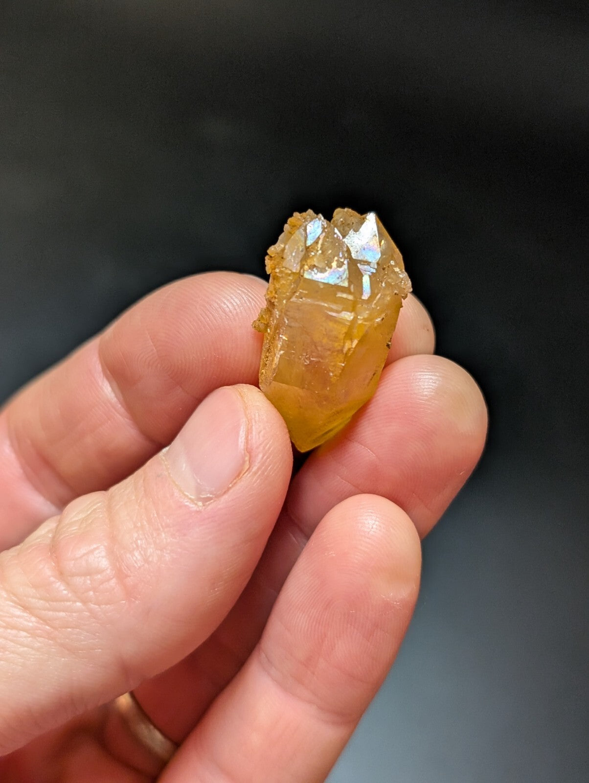 A translucent amber-colored crystal with a faceted, geometric shape and natural mineral inclusions.