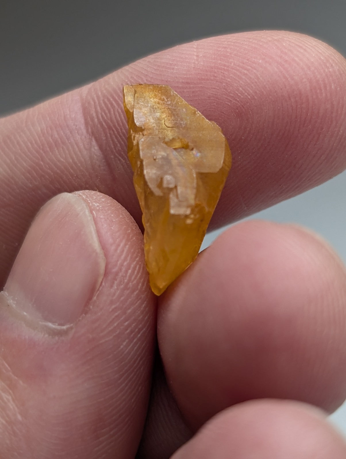 A translucent amber arkansas quartz crystal with rough jagged surface and natural white crystalline inclusions
