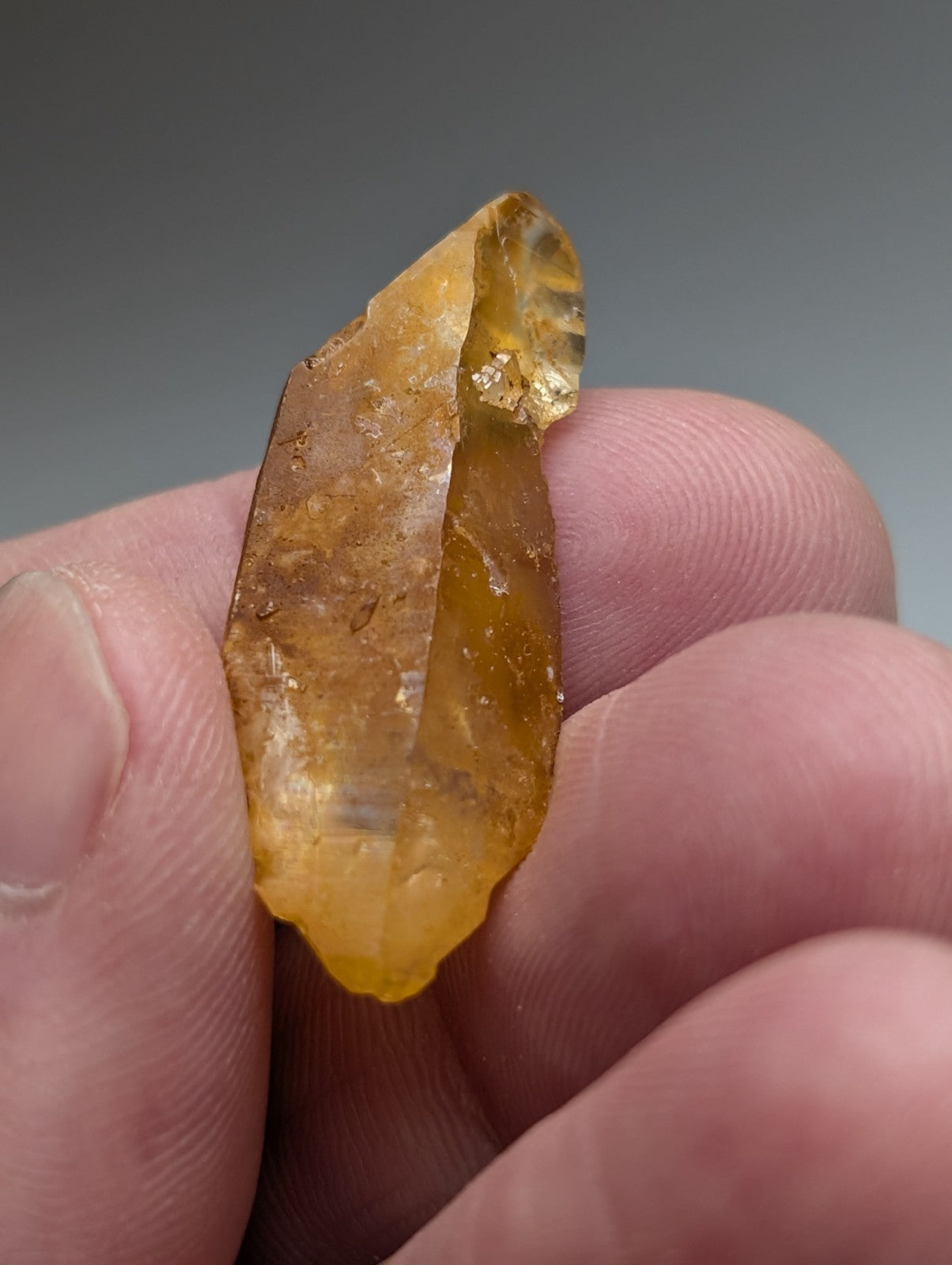 A translucent amber-colored arkansas quartz crystal with rough jagged surface and natural iridescence unique ooak