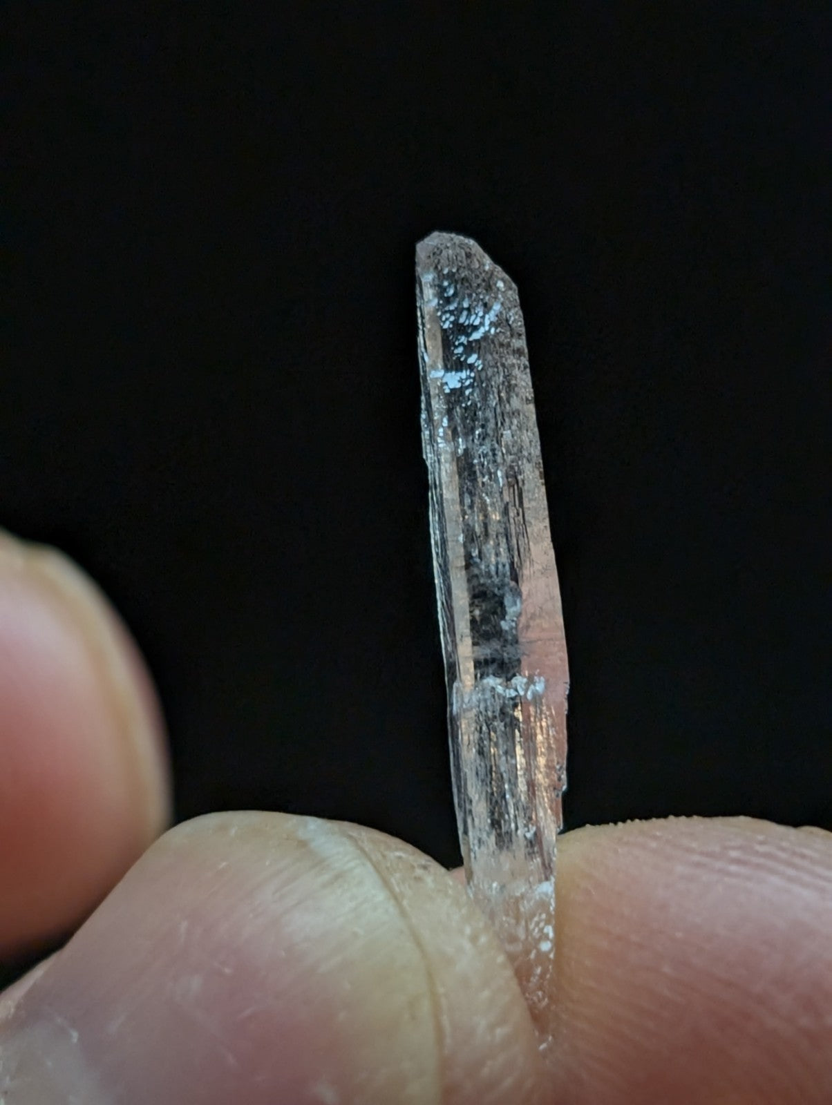 A translucent, clear quartz crystal with subtle internal striations and a slightly roughened top edge.