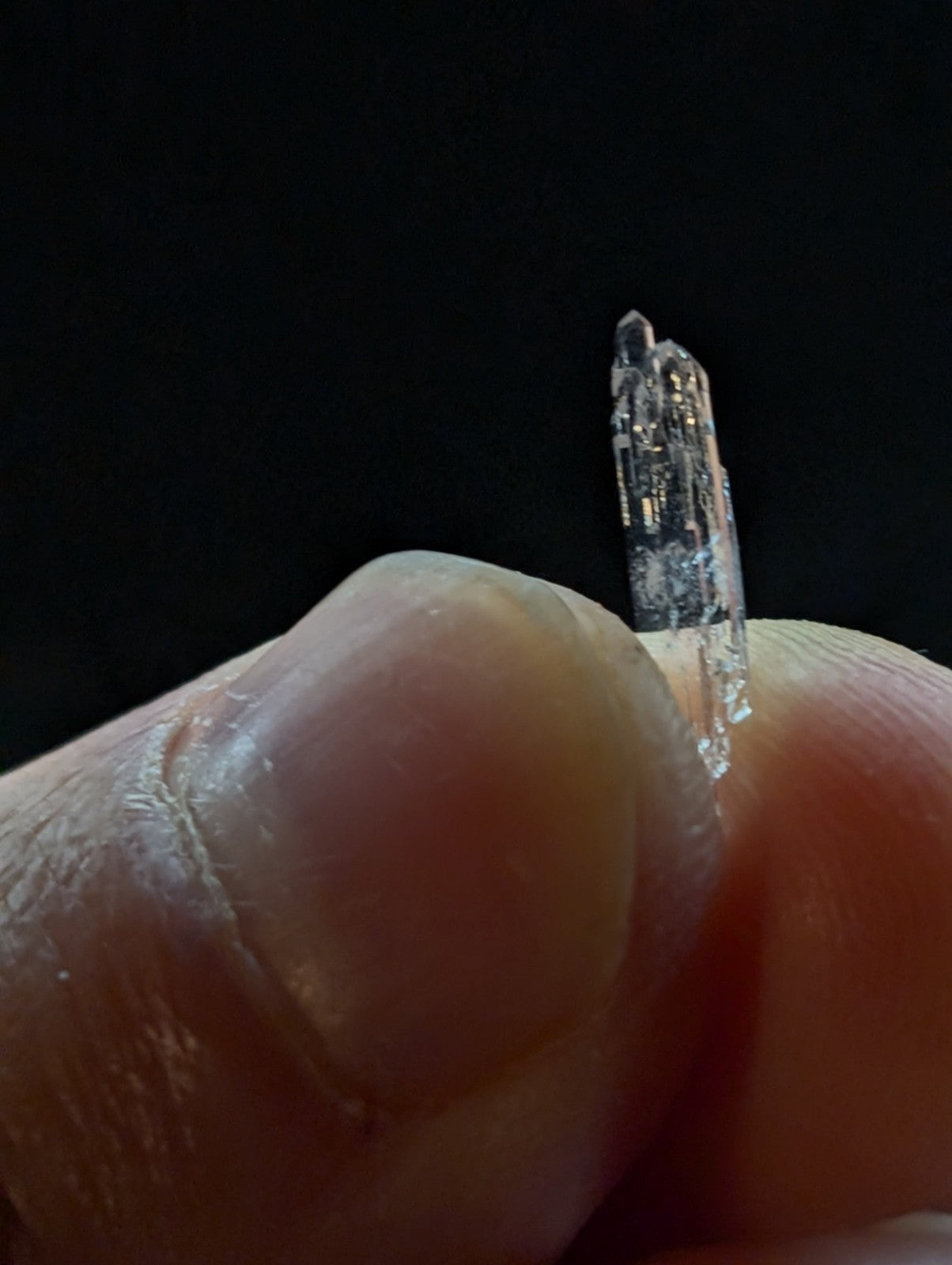 A translucent, clear quartz crystal with a pointed tip and visible internal striations.