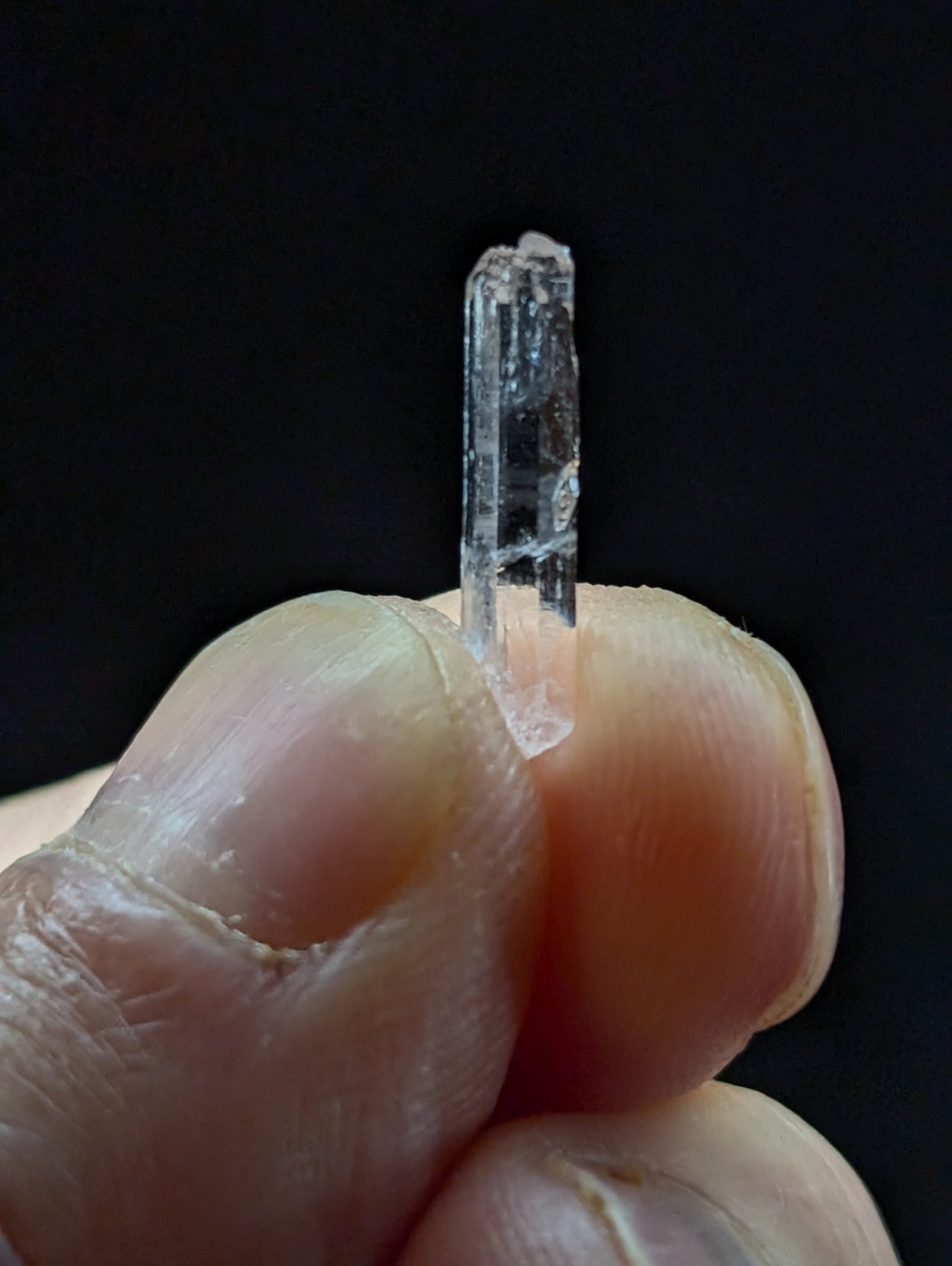 A clear, translucent quartz crystal with visible internal striations and a pointed tip.