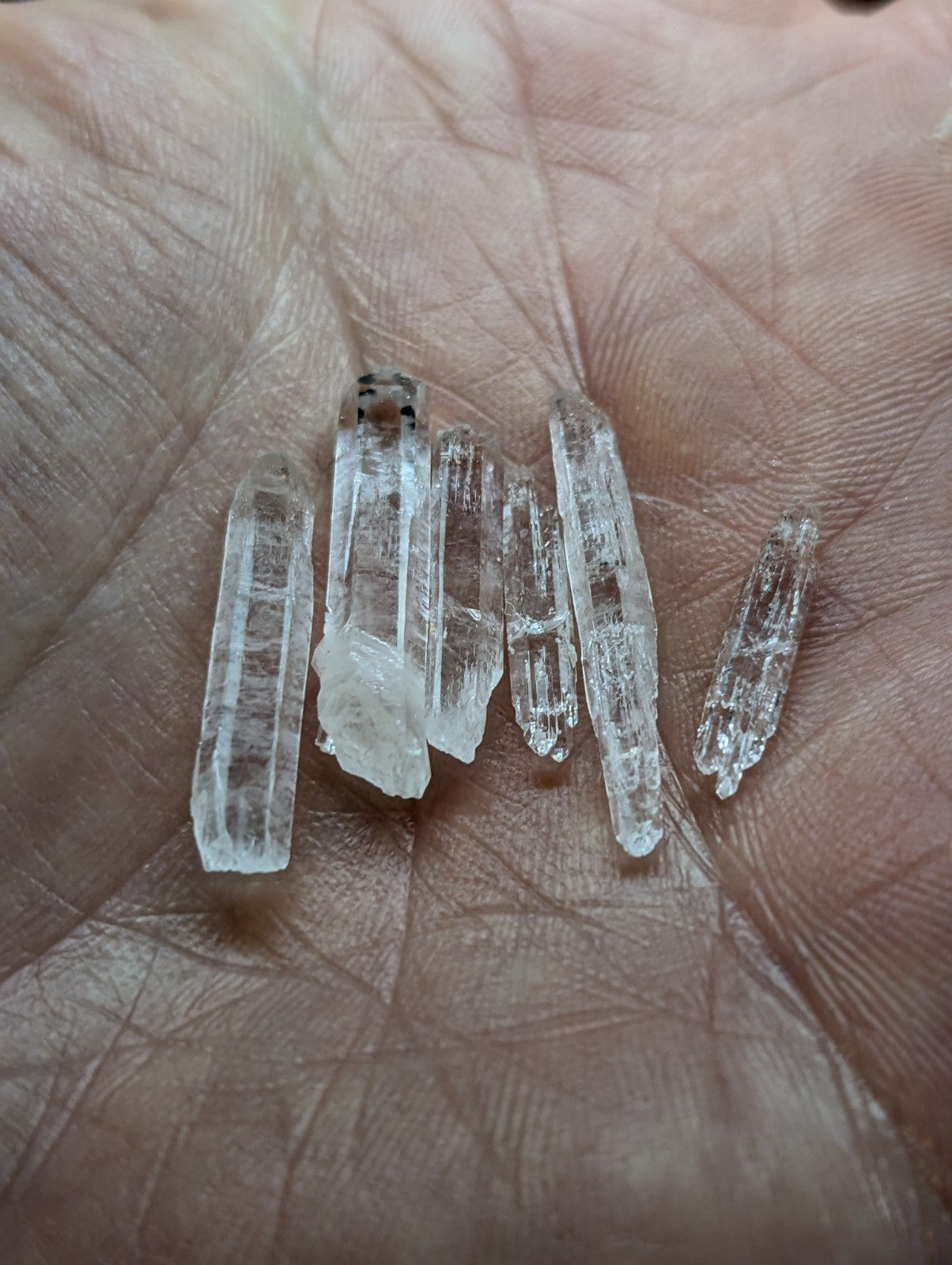 A collection of clear, translucent quartz crystals with natural facets and slight imperfections.