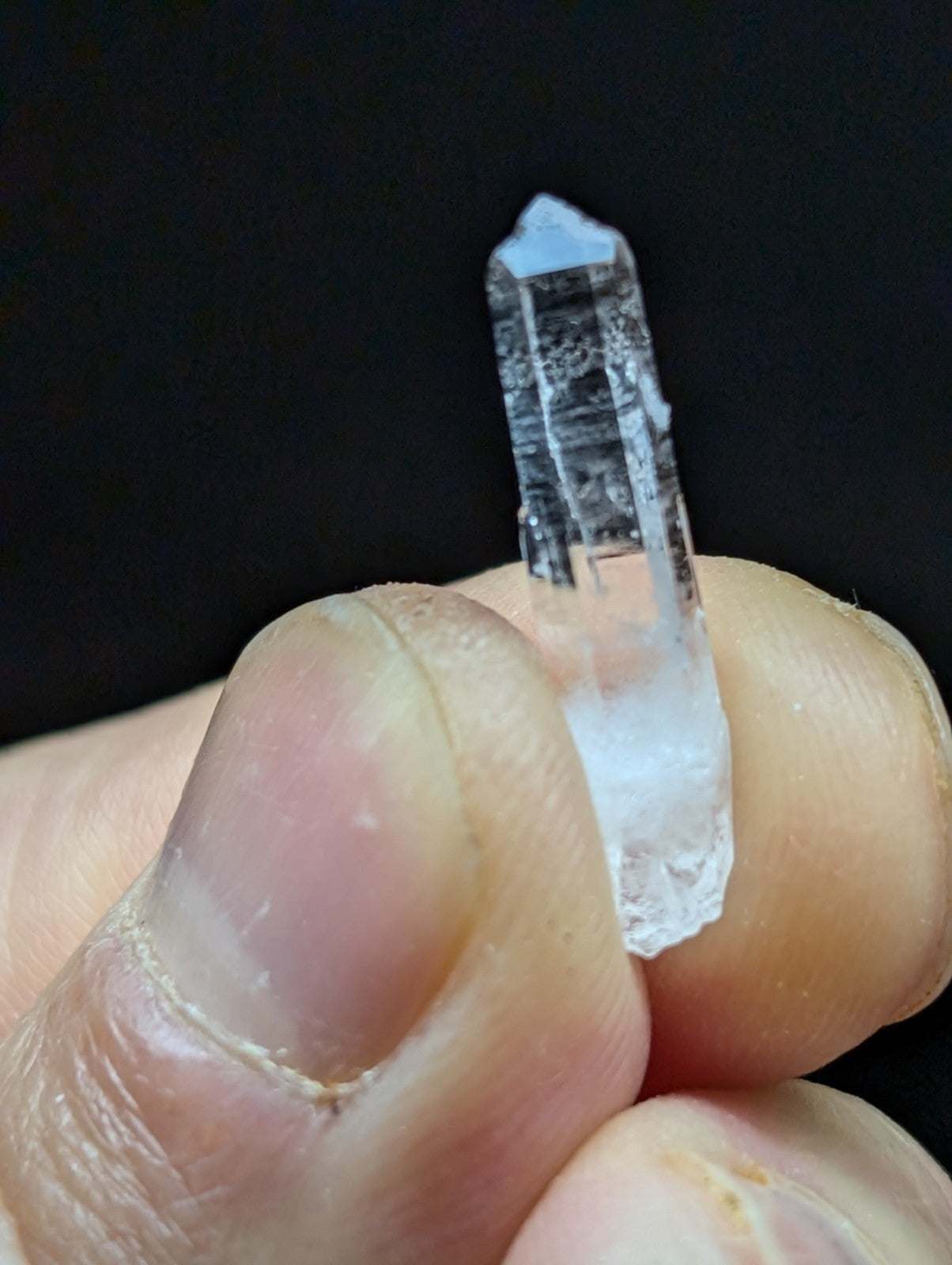 A clear, translucent quartz crystal with a pointed tip and visible internal striations.