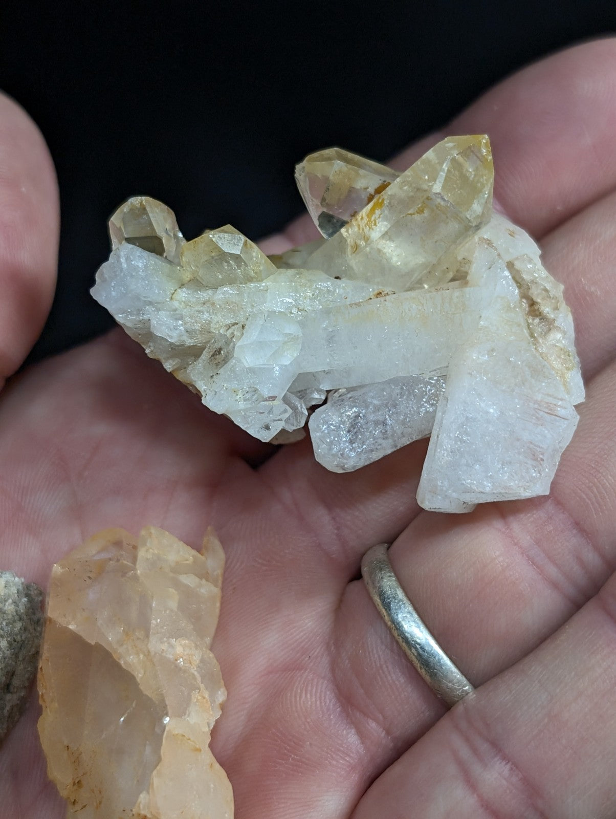 A cluster of translucent yellow and white quartz crystals held in a hand.