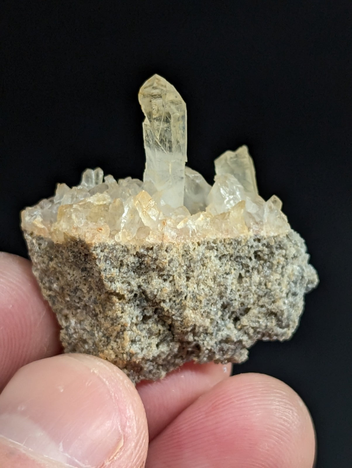 A translucent, pale yellow crystal cluster emerging from a rough gray rock base.