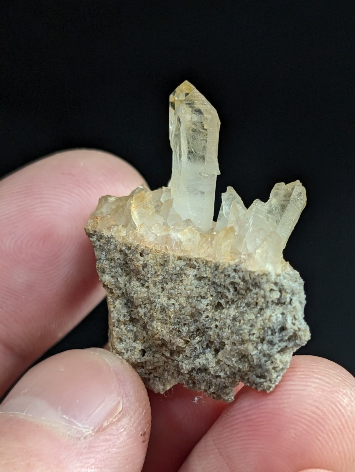 A translucent, pale yellow quartz crystal cluster emerging from a rough gray rock matrix.