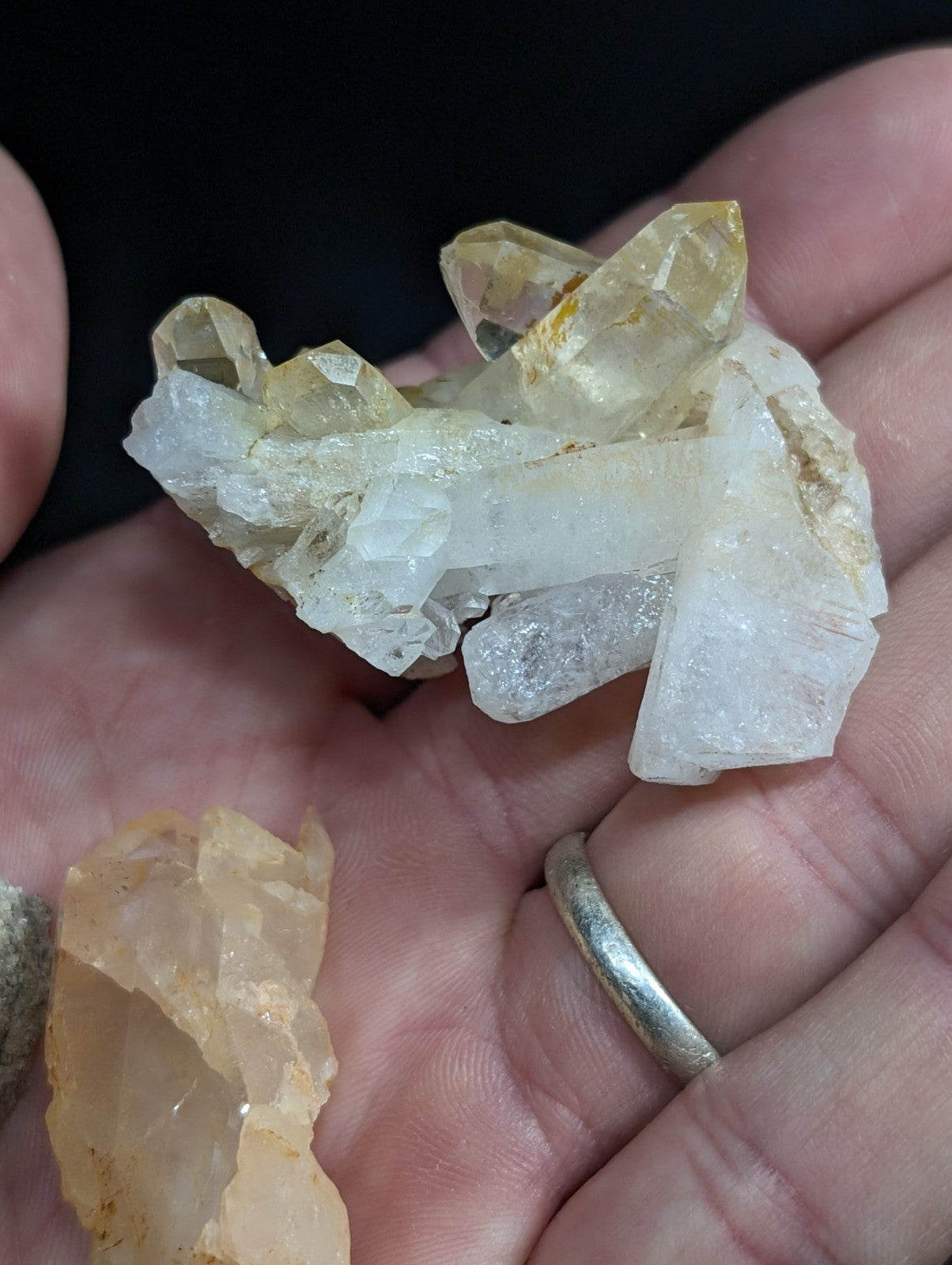 A cluster of translucent yellow and clear quartz crystals held in a hand.