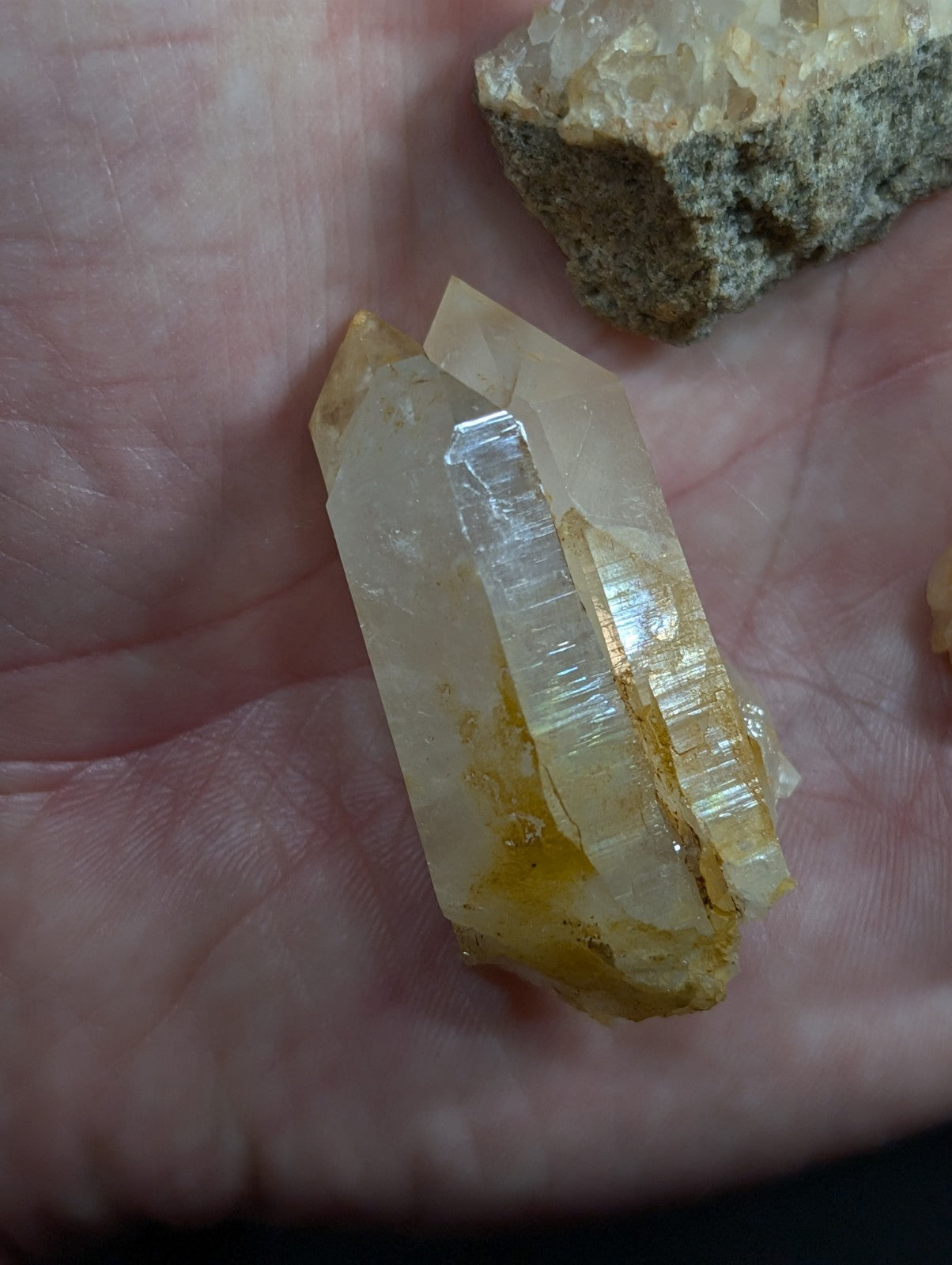 A translucent yellowish quartz crystal with visible striations and a rough, natural base.