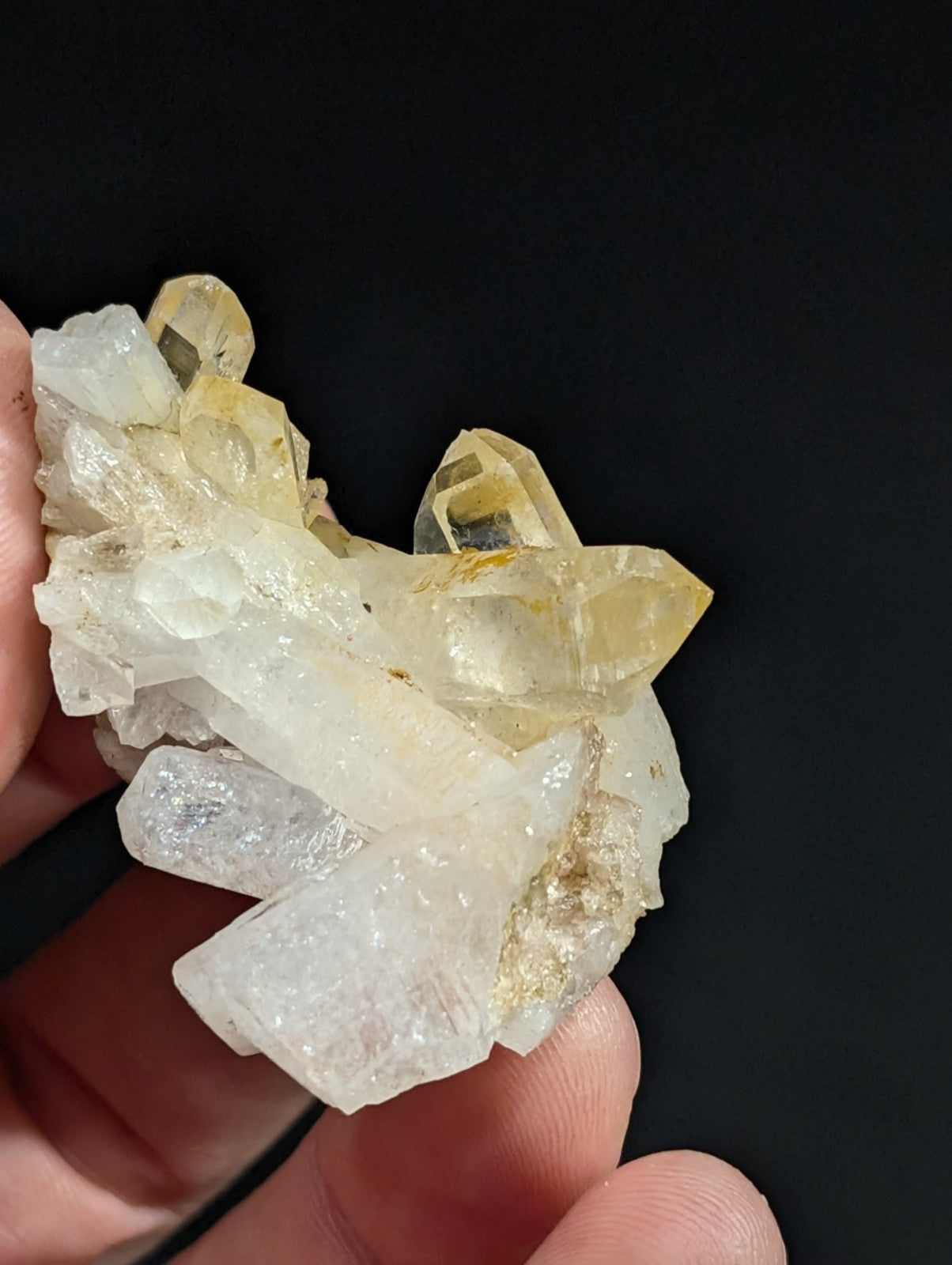 A cluster of translucent quartz crystals, featuring a mix of clear and pale yellow hues with sharp, faceted edges.