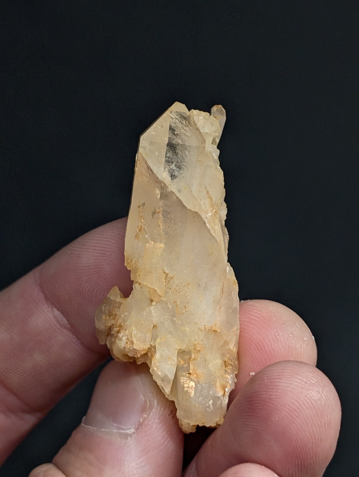 A translucent, pale yellow quartz crystal with a rough, jagged surface and golden mineral inclusions.