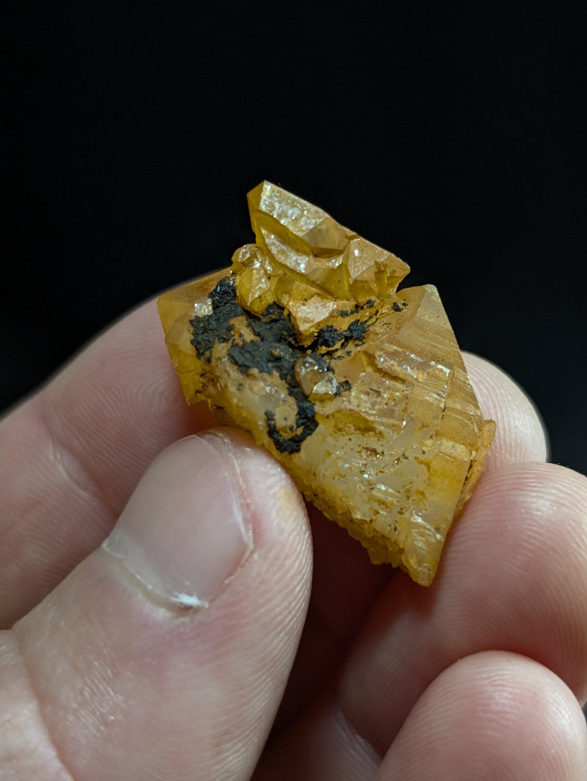 A translucent golden-yellow mineral specimen with sharp, crystalline facets and dark inclusions.