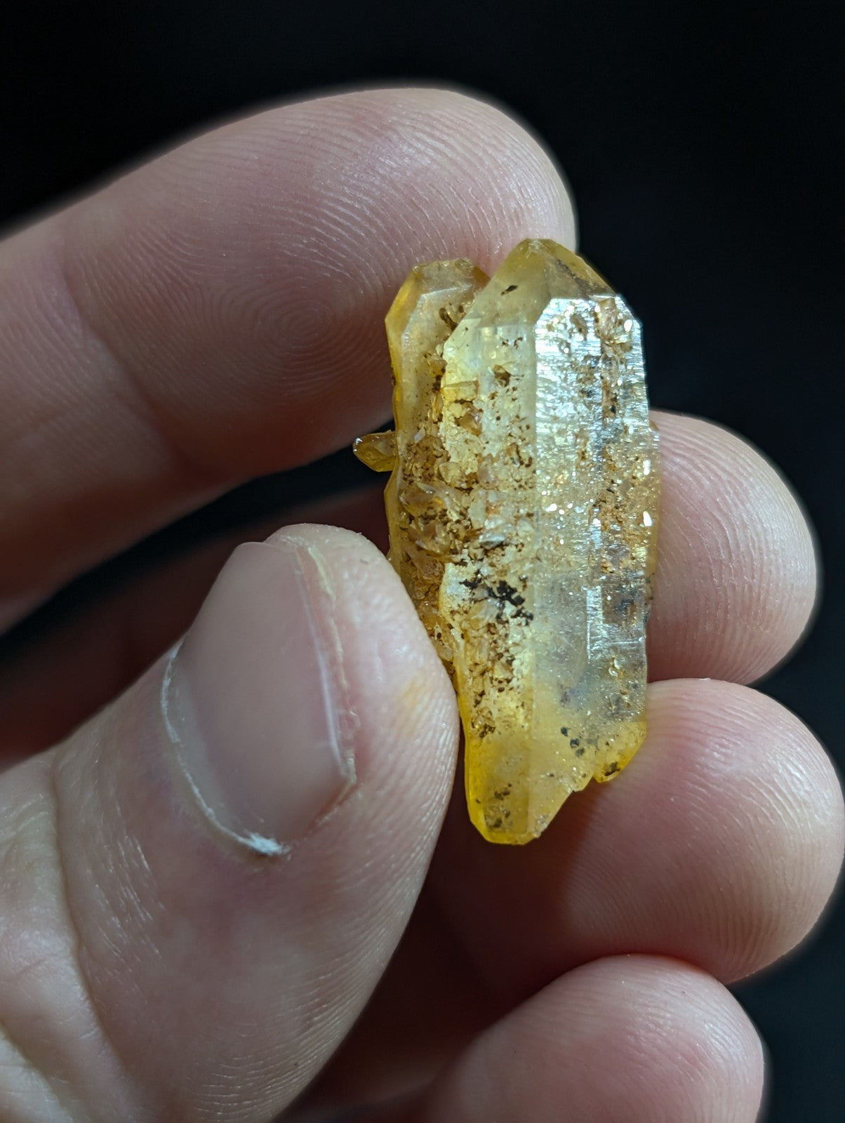 A translucent yellow crystal with a faceted, geometric structure and embedded golden inclusions.