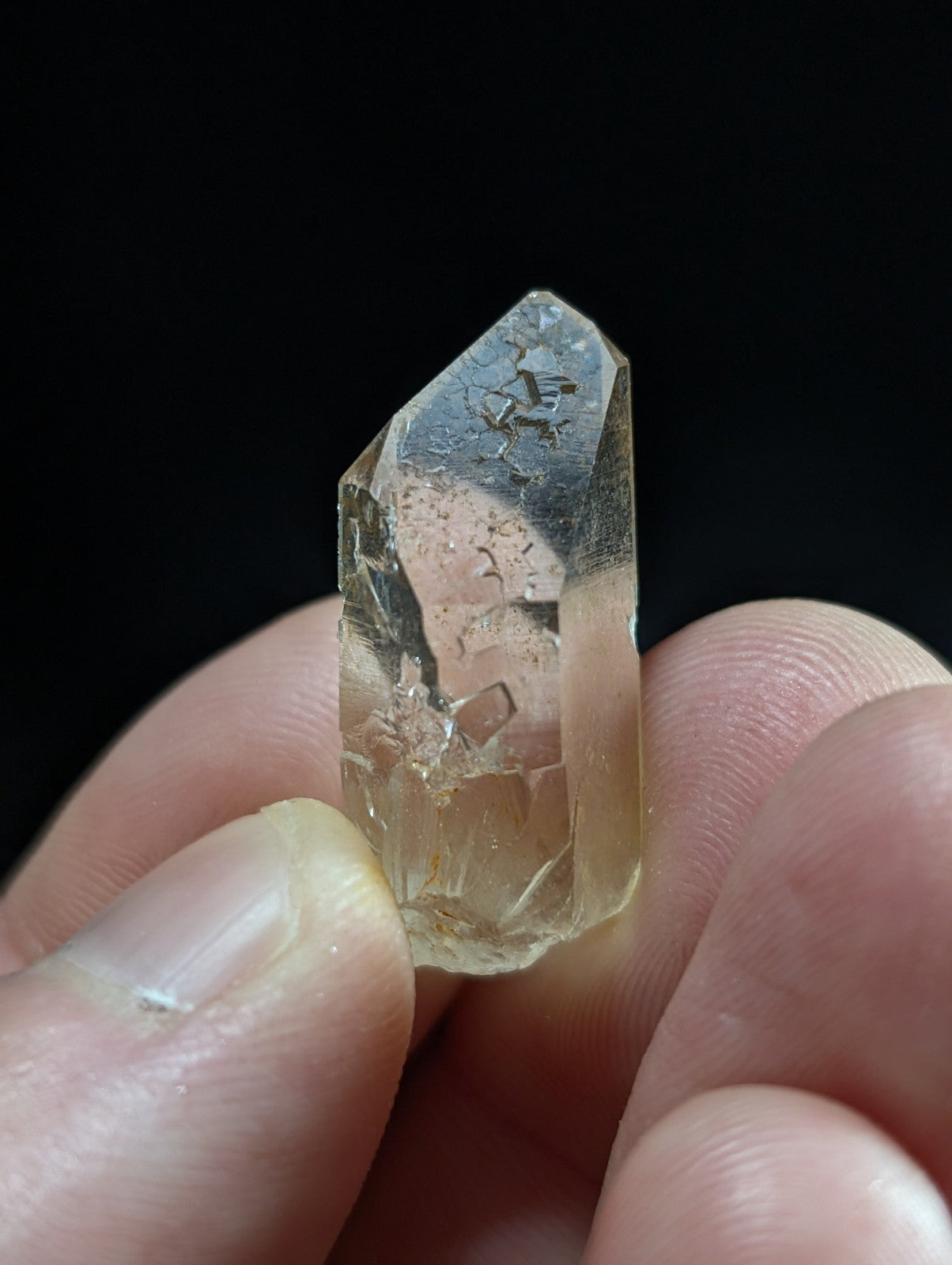 A translucent, pale yellowish quartz crystal with visible internal inclusions and a pointed tip.