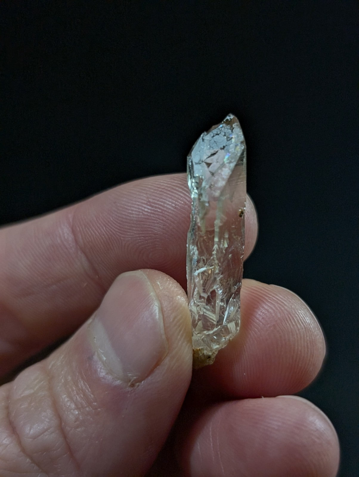 A translucent, pale greenish quartz crystal with visible internal fractures and a pointed tip.