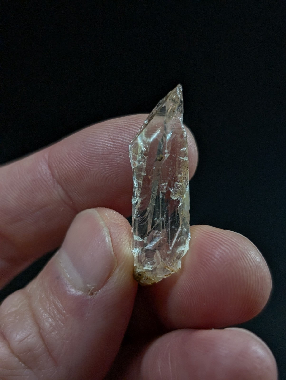 A translucent, pale yellow crystal with a jagged, faceted surface and visible internal striations.