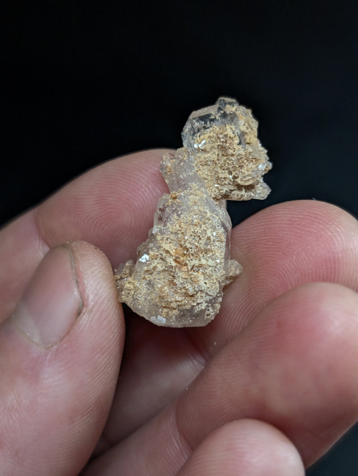 A translucent, crystalline mineral specimen with a rough, earthy texture and golden-brown matrix.