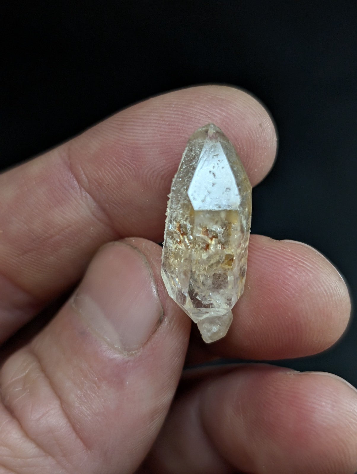 A translucent, pale yellow quartz crystal with a pointed tip and visible internal inclusions.