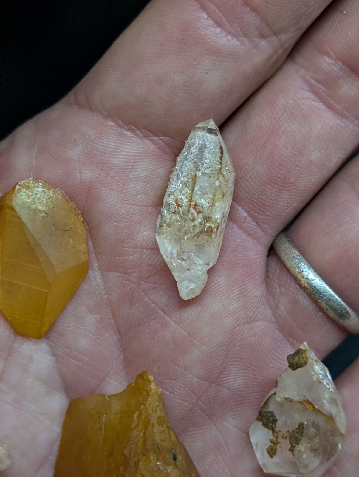 A translucent, pale yellow crystal with a faceted cut and golden inclusions rests gently in the palm of a hand.