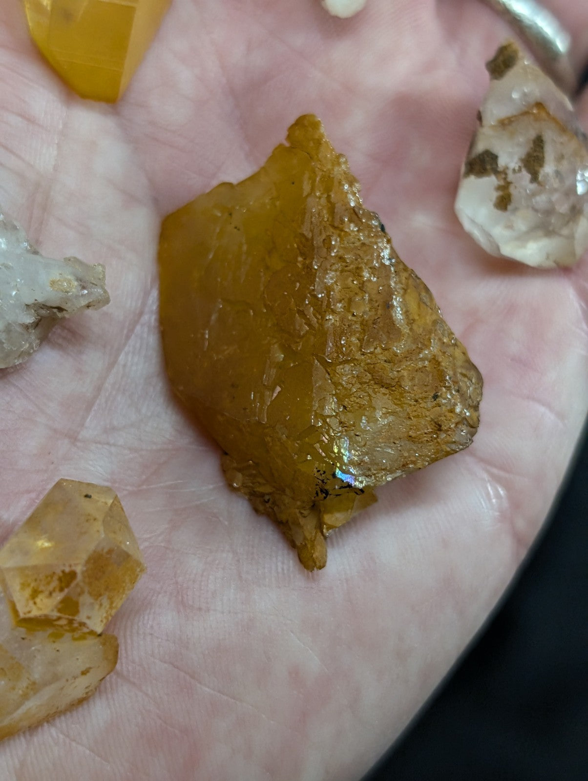 A translucent golden-yellow crystal with a rough, irregular surface and subtle iridescent highlights.