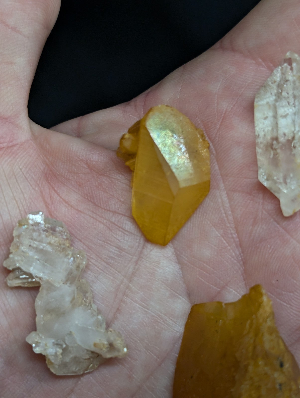 A faceted golden-yellow crystal held in a hand.