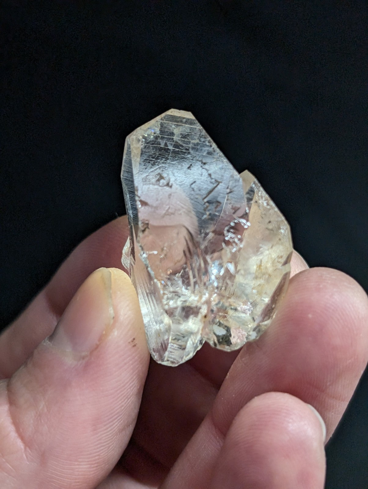 A translucent, clear quartz crystal cluster with visible internal inclusions and a faceted, geometric structure.