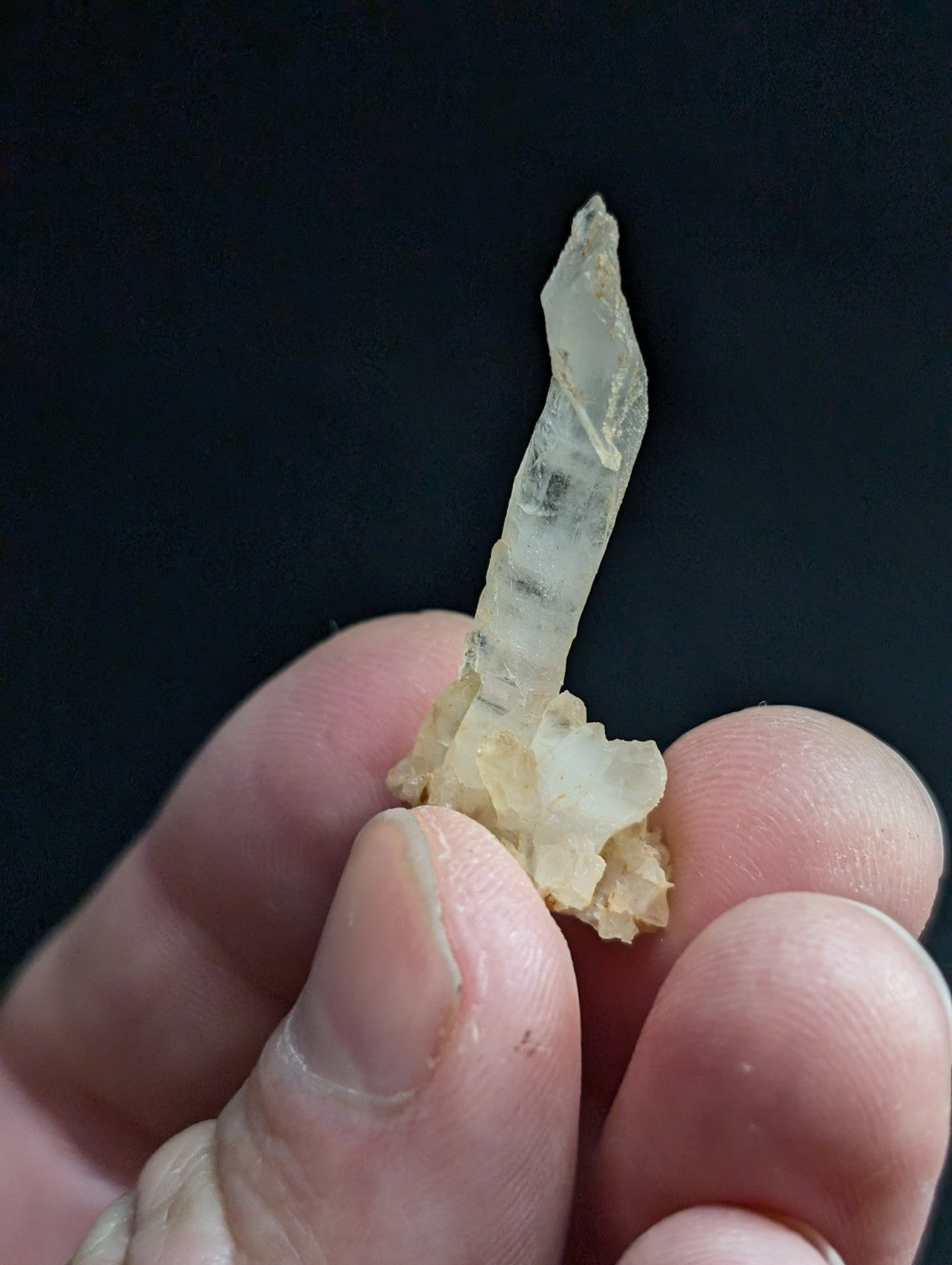A translucent, pale quartz crystal with a pointed tip and visible internal striations.