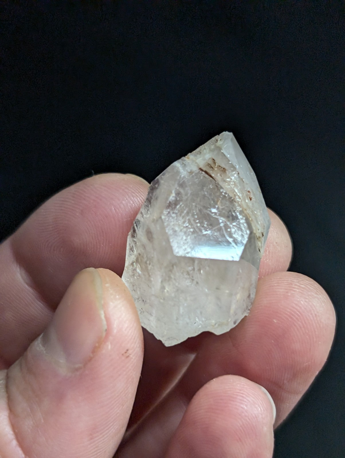 A translucent, clear quartz crystal with a pointed tip and natural facets.